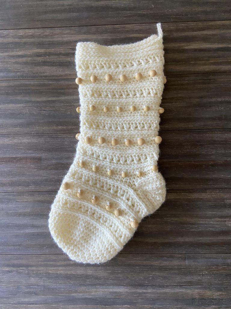 overhead view of cream Christmas stocking with wooden beads