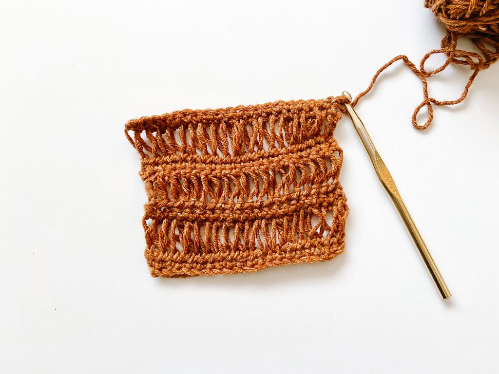 brown crochet fabric piece showing drop stitch on white background