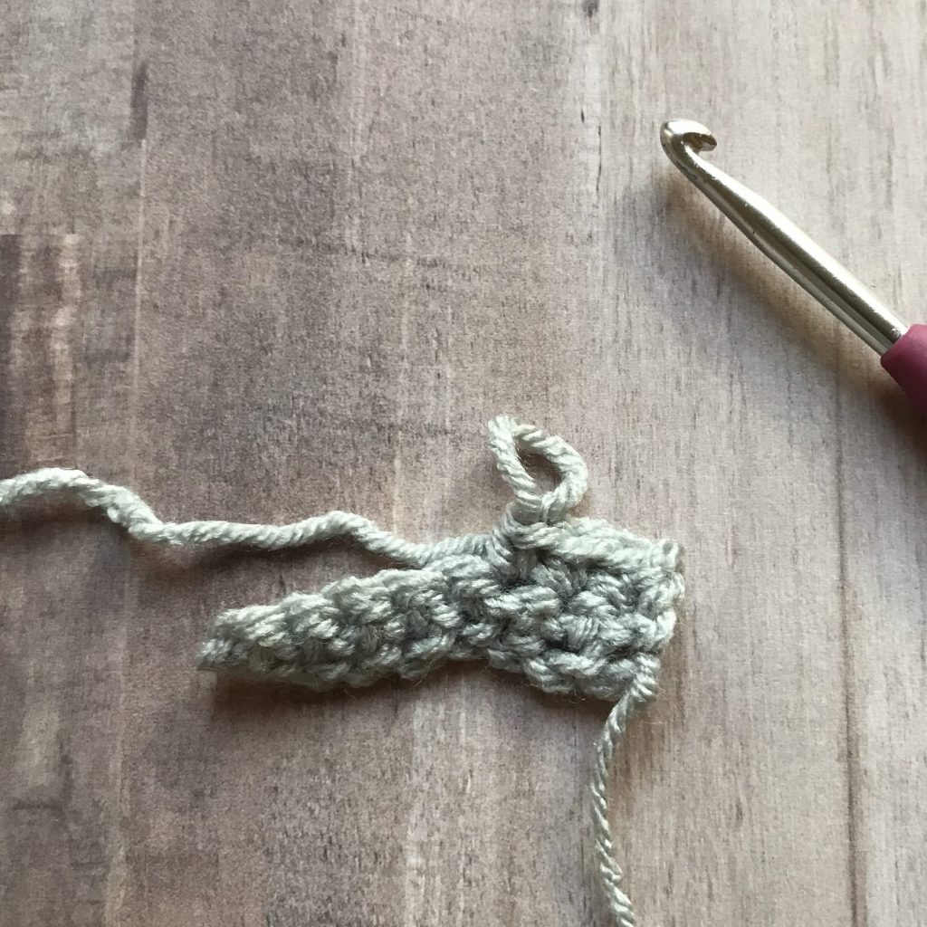 overhead view of crochet hook next to crochet fabric with loop