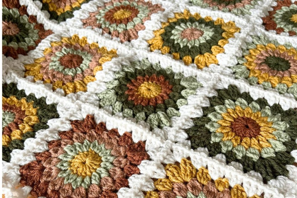 sunflower granny squares in various shades of green, brown and yellow joined with white crochet border
