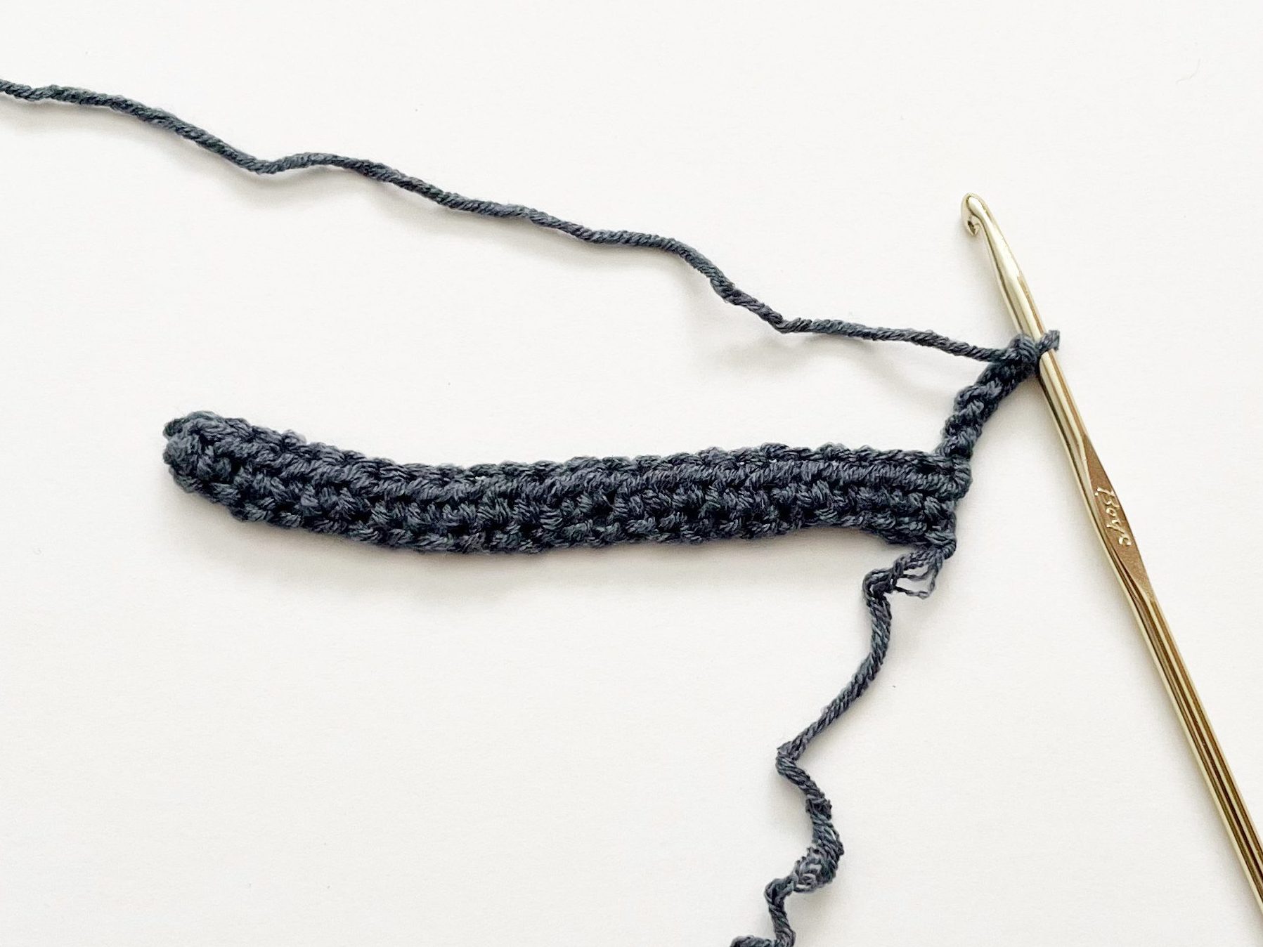 denim blue yarn sample with gold hook on white background