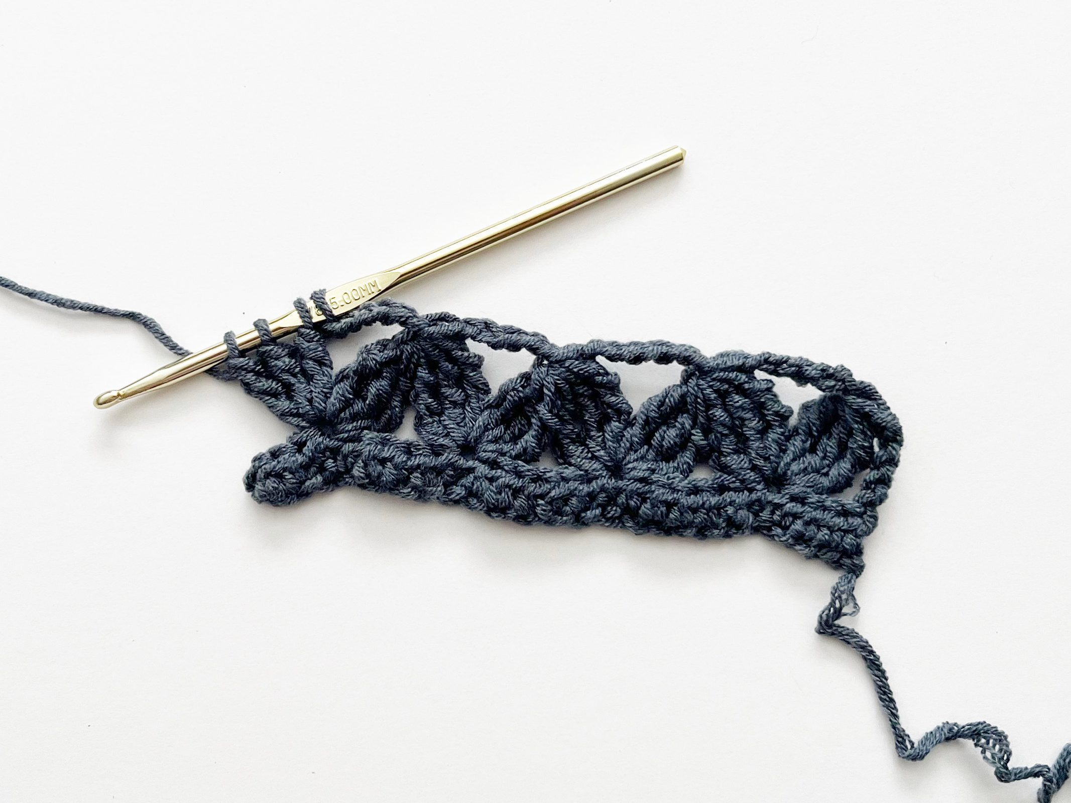 denim blue yarn and gold hook demonstrating a double treble crochet group