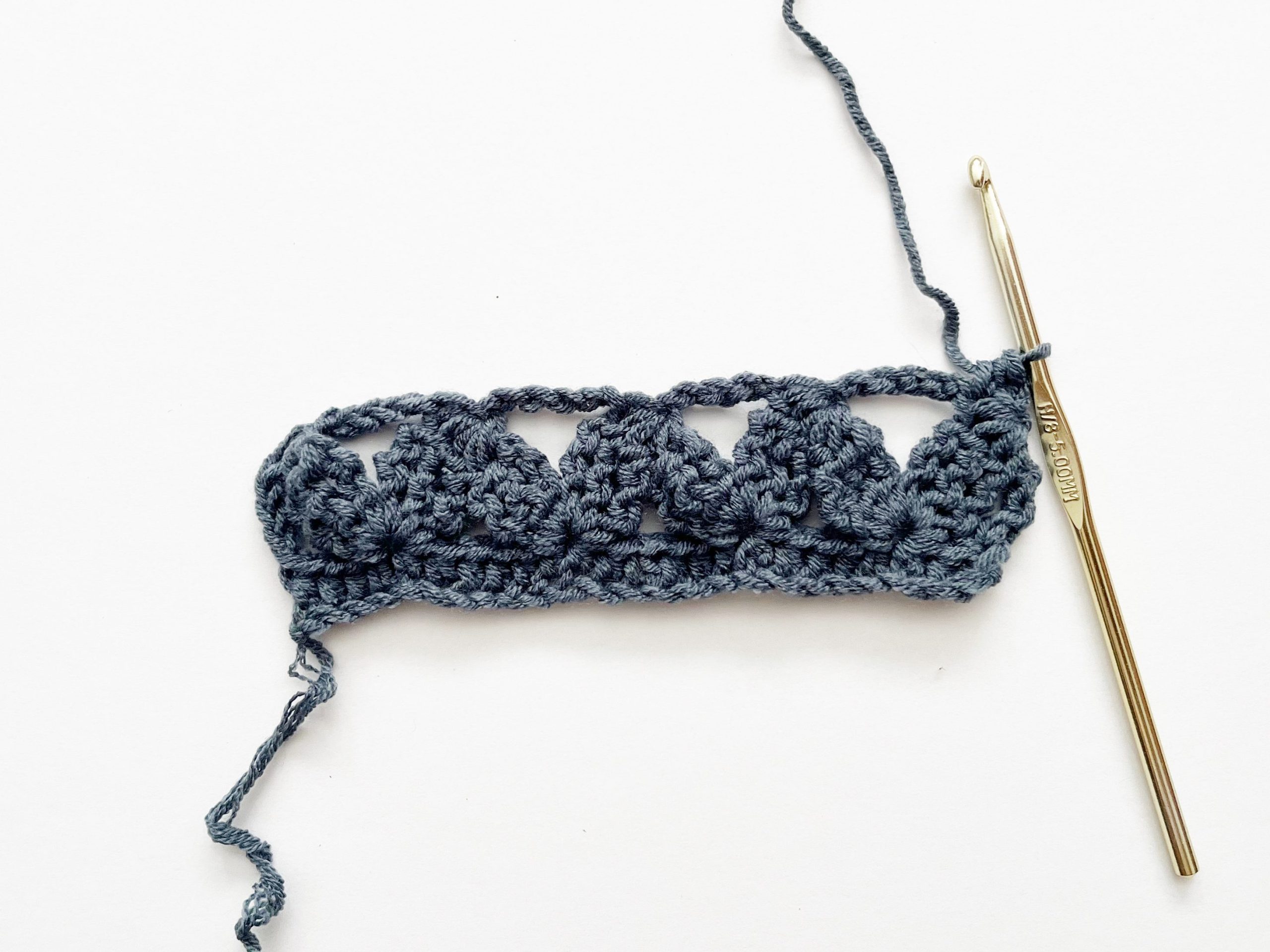blue yarn and gold crochet hook showing placement of half double crochet stitch