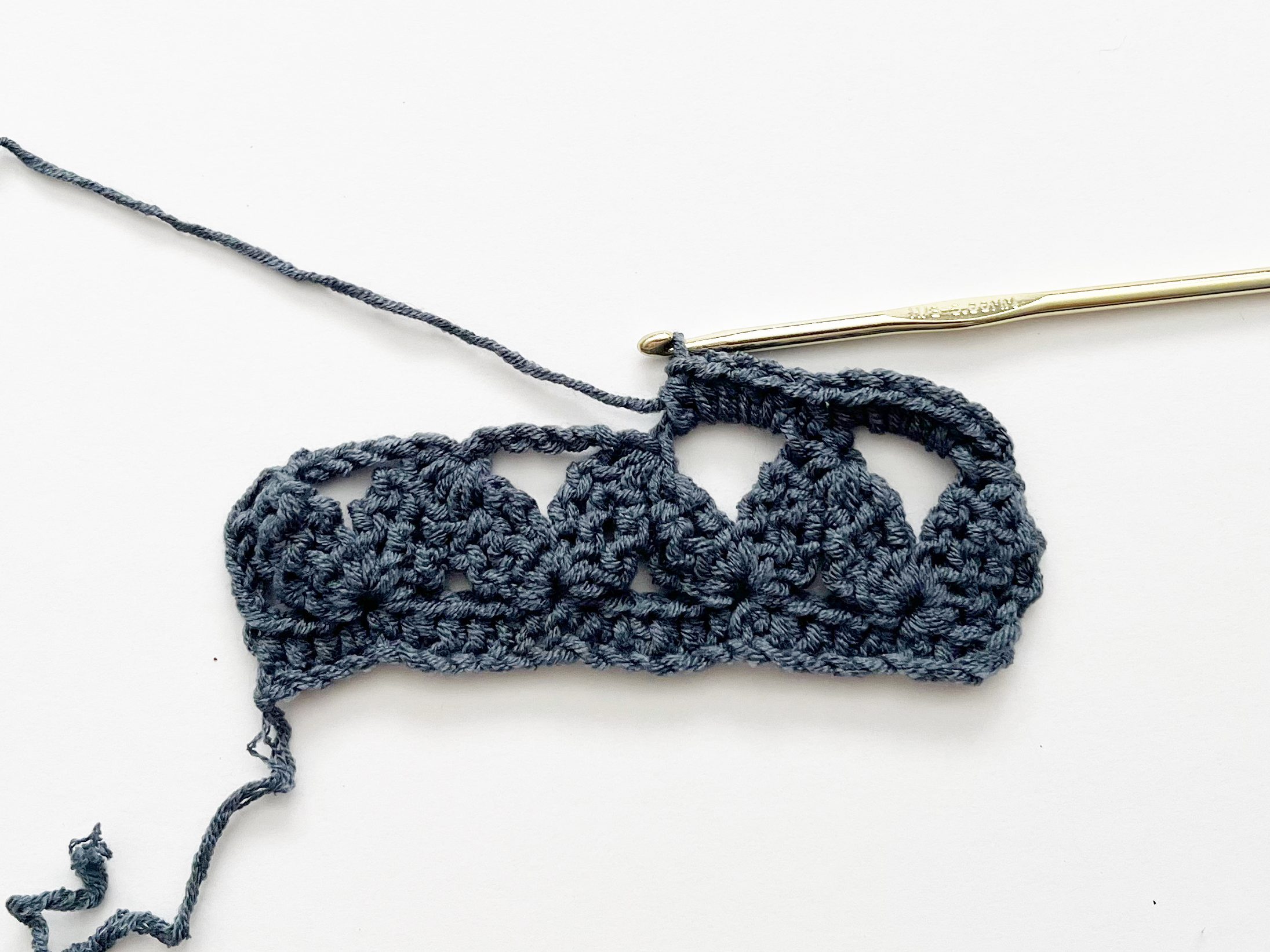 blue yarn and gold crochet hook showing placement of half double crochet stitches