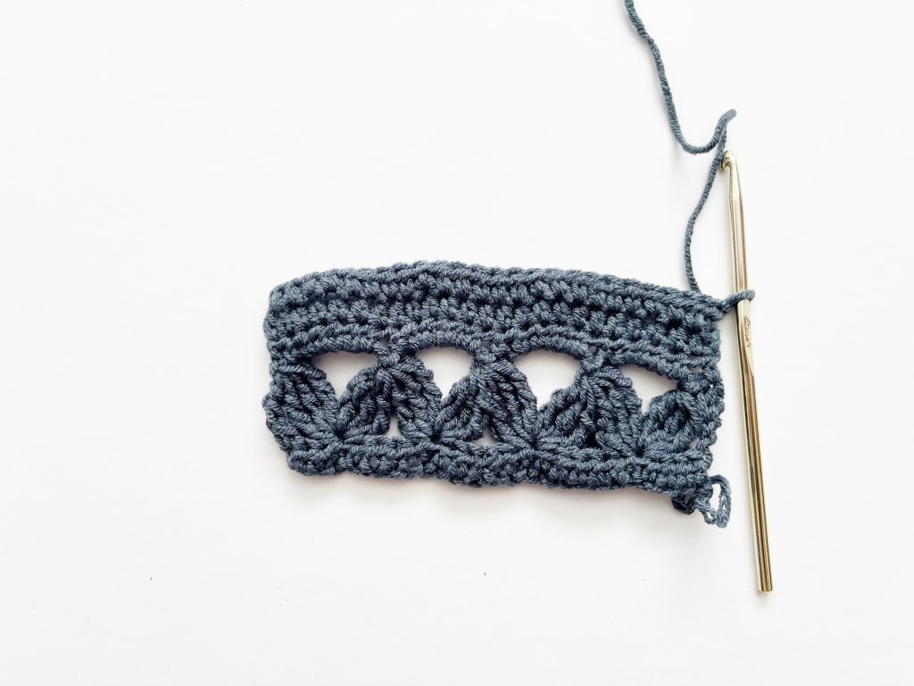 blue yarn and gold hook showing finished half double crochet rows