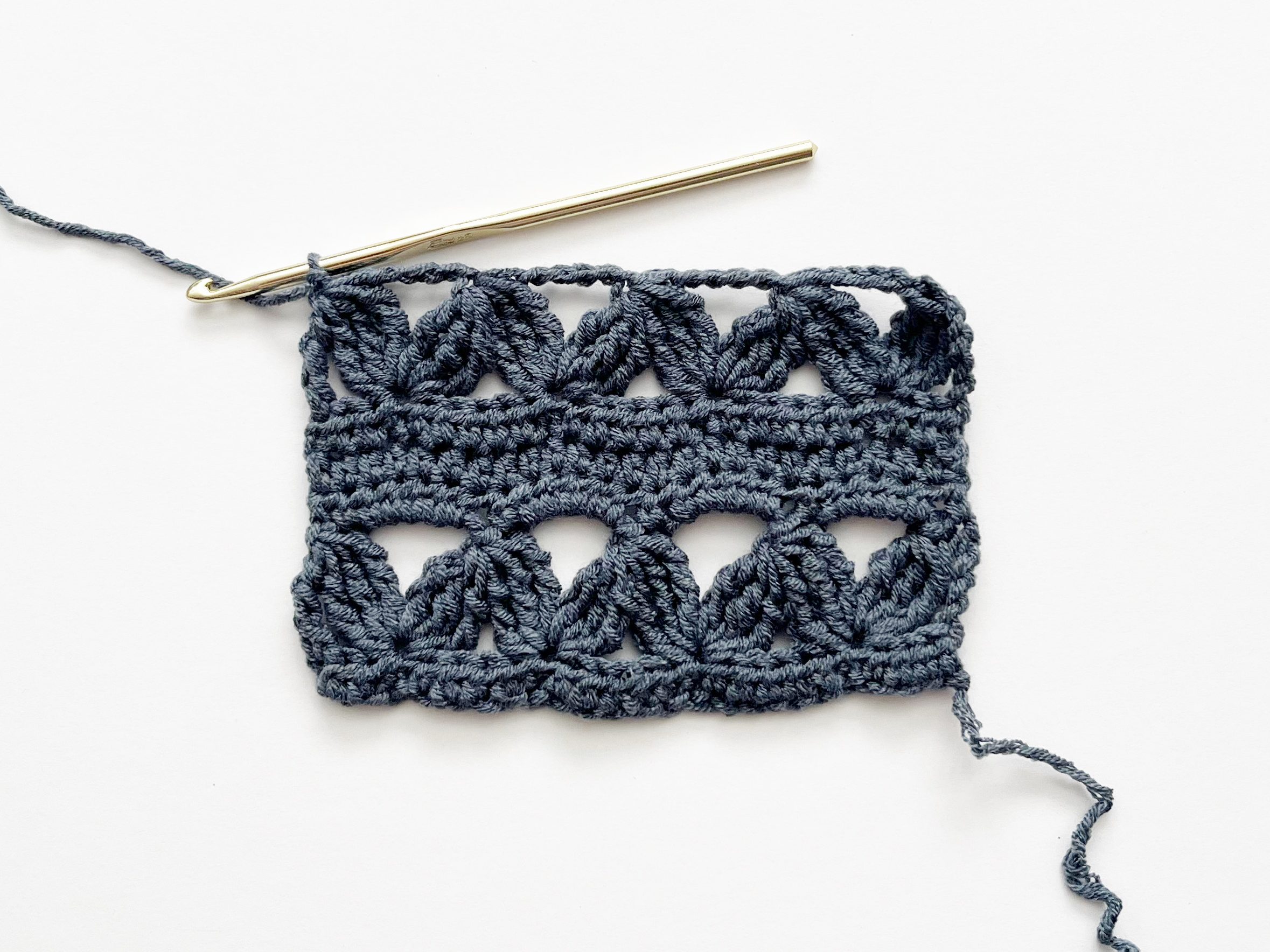 blue yarn and gold hook showing finished zig zag row