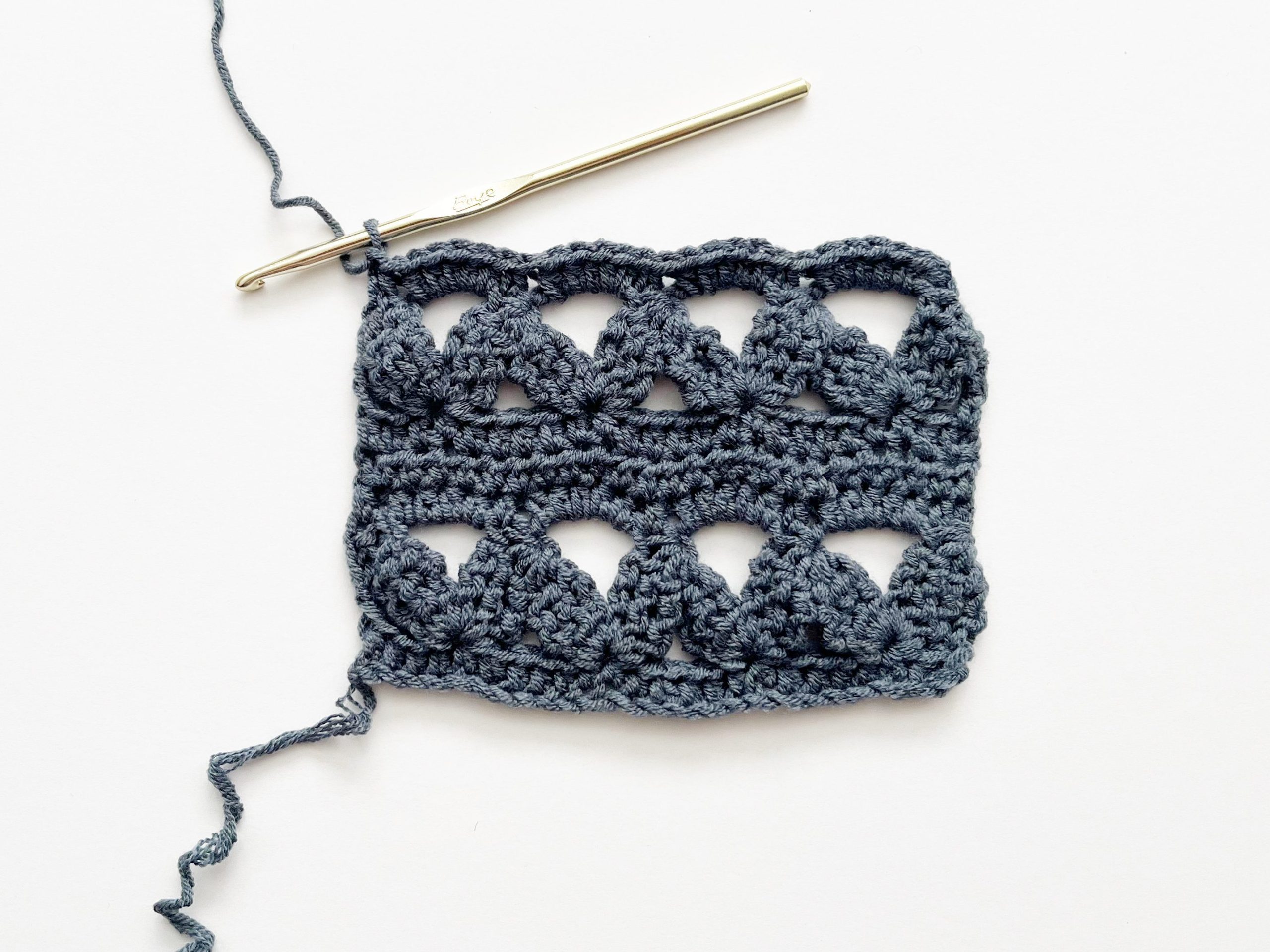 blue yarn and gold hook showing finished 3-Strand Zig-Zag swatch