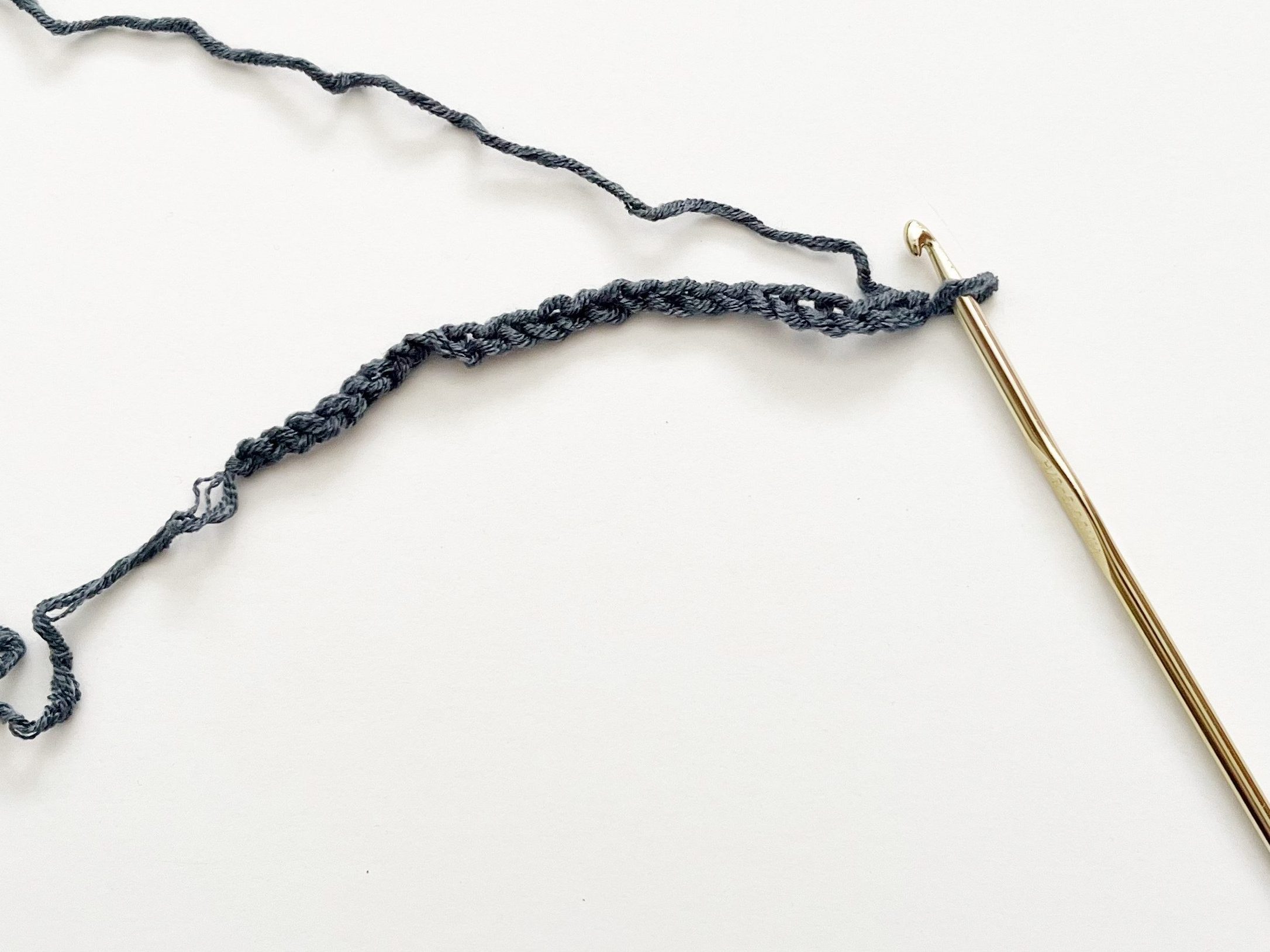 denim blue yarn with a gold hook on white background