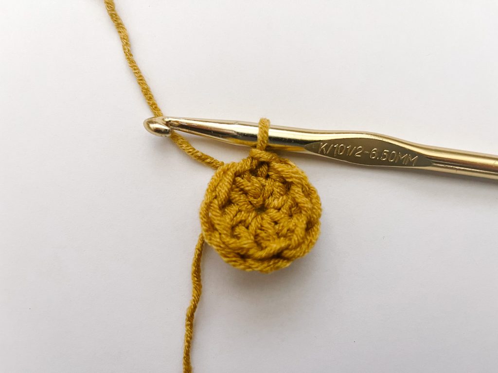 gold crochet hook showing slip stitch join in round on yellow yarn