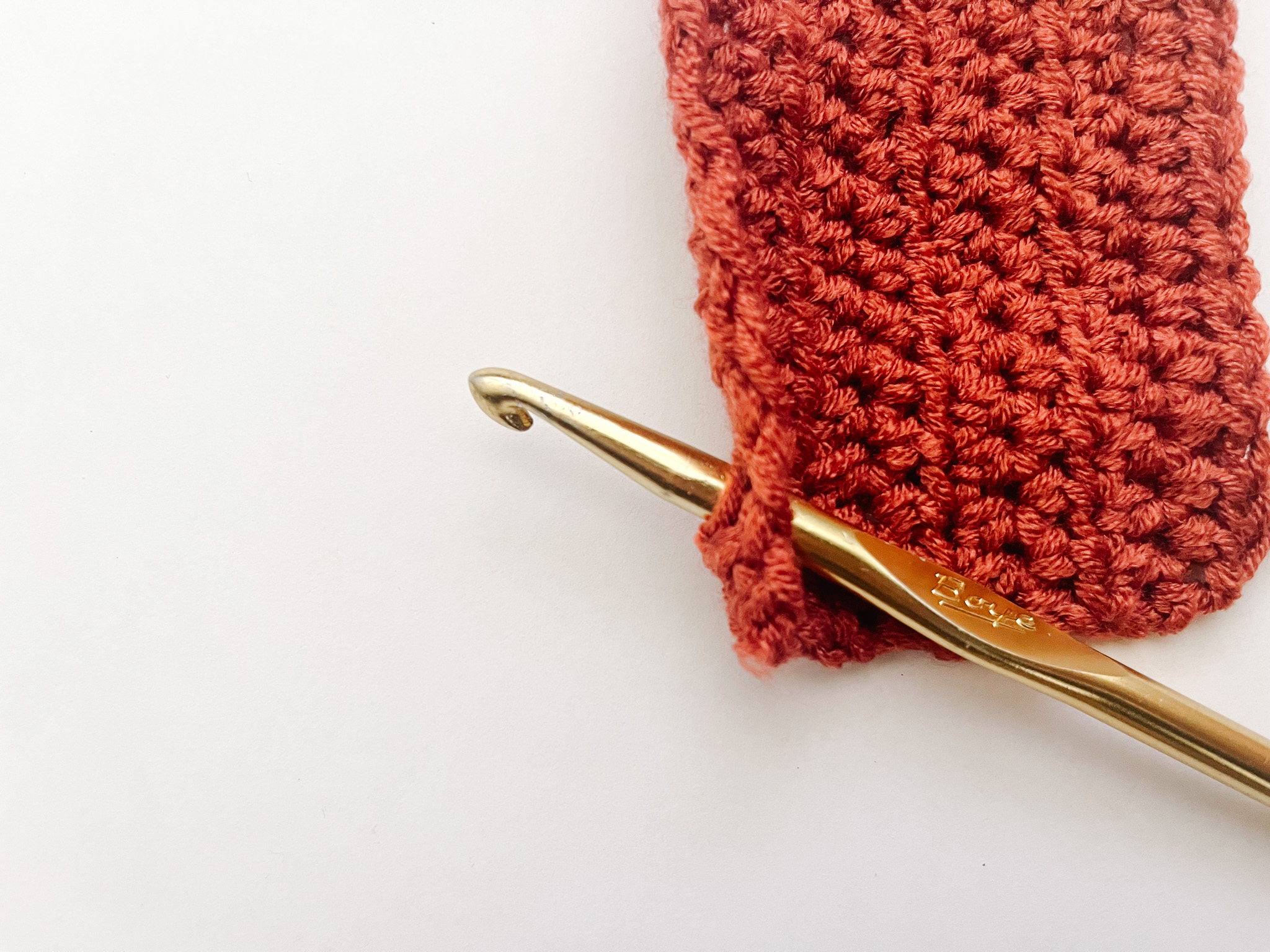 gold hook inserted through red crochet fabric