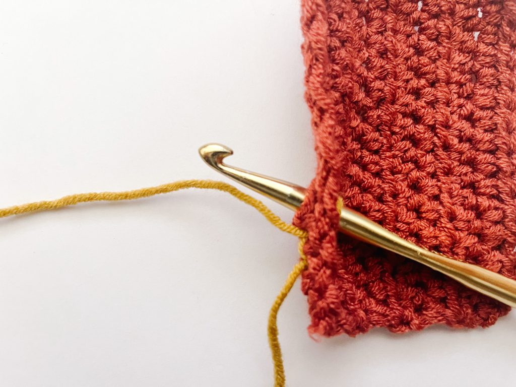 gold hook inserted through red crochet fabric
