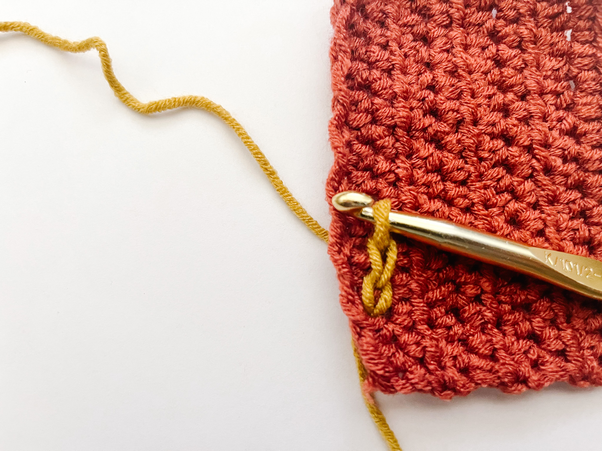 series of three yellow slip stitches on surface of red crochet fabric