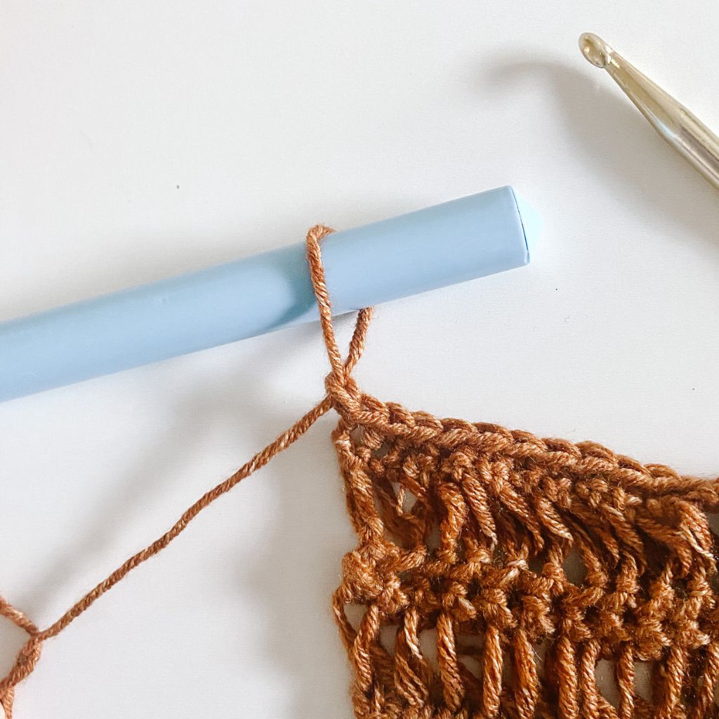brown yarn loop on light blue dowel