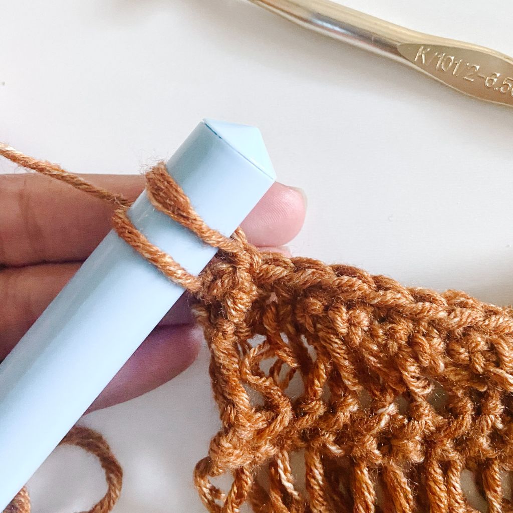 two loops of brown yarn on light blue dowel