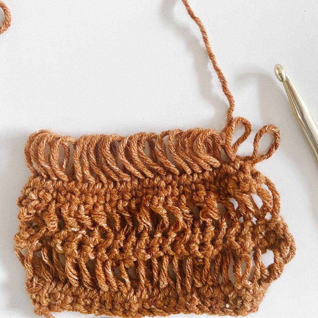 series of crochet drop stitches on brown crochet swatch